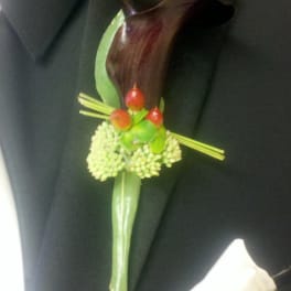 Dark calla lily boutonniere with green berries on a black suit lapel