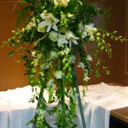 Tall white floral spray on a stand with cascading greenery