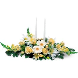 Yellow and white floral centerpiece with two white taper candles