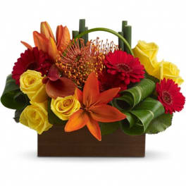 Bright mixed bouquet in a brown box with roses, gerbera daisies, lilies, and tropical blooms