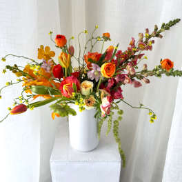 Mixed bouquet in a white vase with orange, pink, and yellow flowers