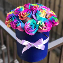 Rainbow-colored roses in a blue hatbox with a pink ribbon