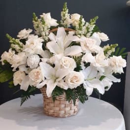 White lilies and roses arranged in a wicker basket