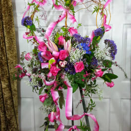 Tall floral spray with pink roses, lilies, and purple accents on a stand