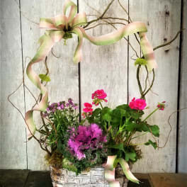 Basket arrangement with pink flowers and ribbon on a twig frame
