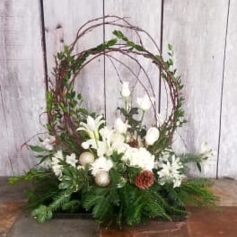 White floral arrangement with a twig wreath and evergreen base