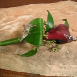 Red calla lily boutonniere with green leaves and silver accents