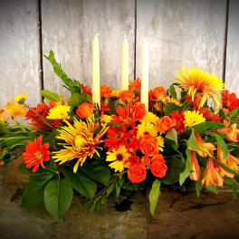 Orange and yellow floral centerpiece with three taper candles