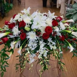 Large floral spray with red roses, white lilies, and cascading greenery