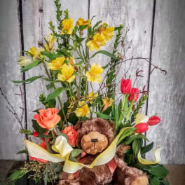 Flower arrangement with a teddy bear, roses, tulips, and yellow blooms