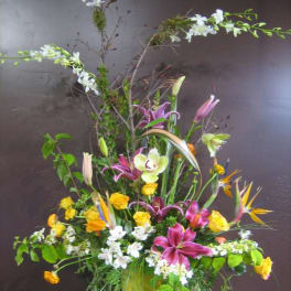 Tall mixed floral arrangement with lilies, roses, orchids, and bird of paradise