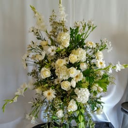 Tall white floral arrangement with roses, daisies, and lilies