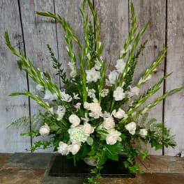 White floral arrangement with tall green spikes and roses in a low container