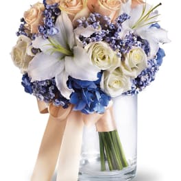 Bouquet of peach and white roses with blue flowers in a glass vase