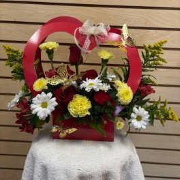 Red basket arrangement with red roses, white daisies, and yellow carnations