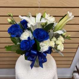 Blue and white bouquet with lilies and roses tied with a blue ribbon