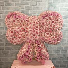 Pink rose arrangement shaped like a bow on a pedestal