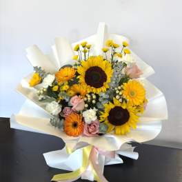 Bouquet with sunflowers, orange gerberas, pink roses, and white blooms wrapped in white paper