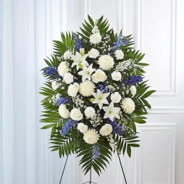 Standing funeral spray of white and blue flowers on an easel
