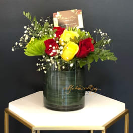Red and yellow roses in a glass vase with baby's breath