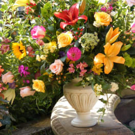 Colorful mixed flower arrangement in a cream urn vase