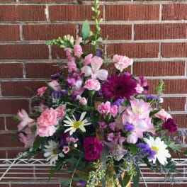 Mixed pink and purple flower arrangement in a basket