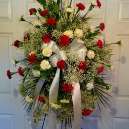 Standing floral spray with red and white carnations and white ribbon