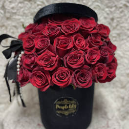 Bouquet of red roses in a black hat box with ribbon