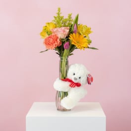 Mixed bouquet in a glass vase with a white teddy bear