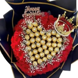Heart-shaped bouquet of red roses and gold chocolates with a Happy Anniversary topper