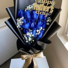 Blue roses with baby's breath in black wrap and a gold Father's Day topper