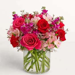 Pink and red roses with pale pink lilies in a glass vase