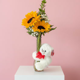 Sunflower bouquet in a glass vase with a white teddy bear