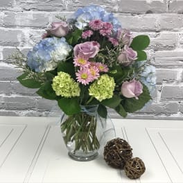 Mixed bouquet of pastel flowers in a clear glass vase