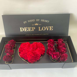 Boxed arrangement of red roses and a heart-shaped cluster of red carnations