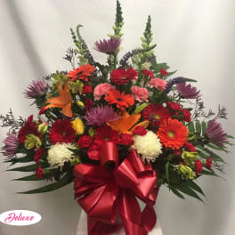 Large mixed bouquet with gerbera daisies, lilies, and a red ribbon bow
