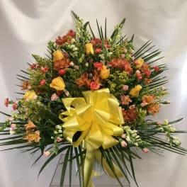 Large mixed flower arrangement with a yellow bow in a clear vase