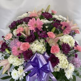 Pink and white mixed flower arrangement with a purple ribbon bow
