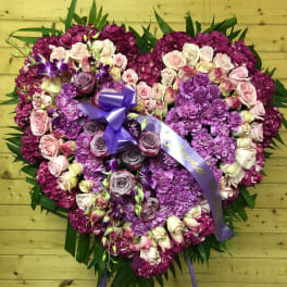 Heart-shaped floral tribute with pink and purple roses and hydrangeas