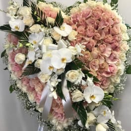 Heart-shaped bouquet of pink and white roses with orchids and ribbon