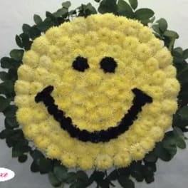 Yellow smiley-face floral wreath with dark eyes and mouth