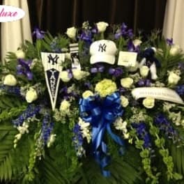 Large funeral spray with white roses, purple flowers, and a blue ribbon