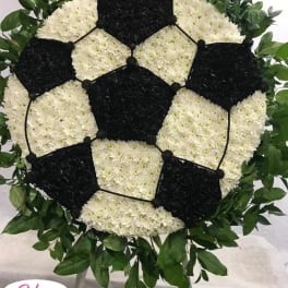 Soccer ball floral tribute on a stand with white and black flowers