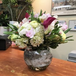 Mixed bouquet of white, pink, and purple flowers in a glass vase