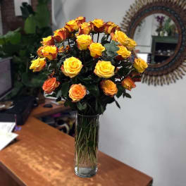 Bouquet of yellow and orange roses in a tall glass vase