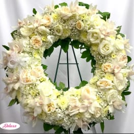 Creamy white floral wreath with roses and orchids on a stand
