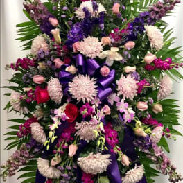 Large standing floral spray with purple and pink flowers and ribbon