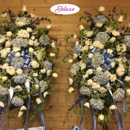 Two large blue and white floral standing sprays with ribbon bows