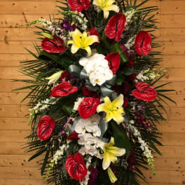 Standing floral spray with red anthuriums, yellow lilies, and white orchids
