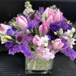 Pink and purple bouquet in a clear square vase